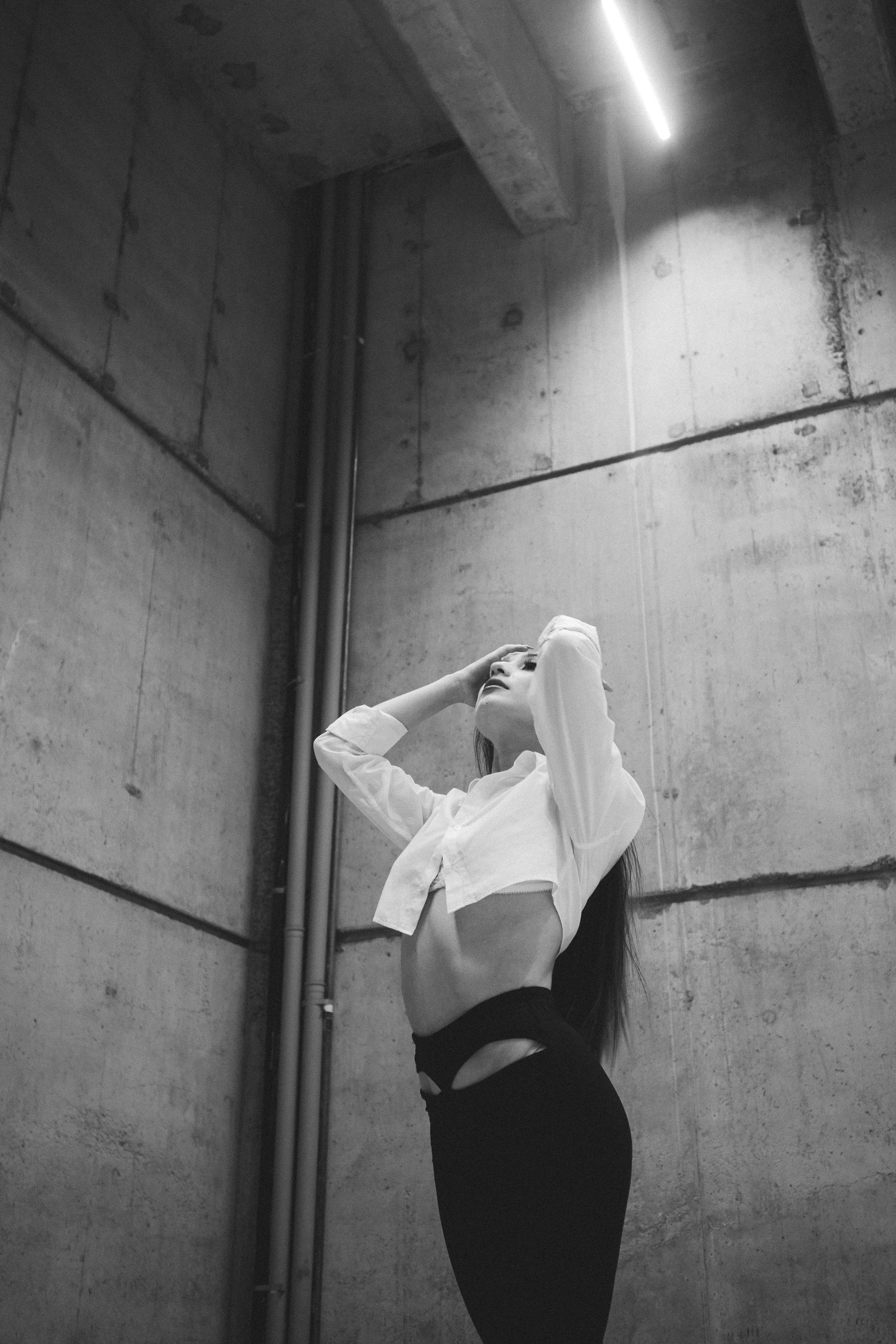 Black and white shot of woman posing in industrial space, low angle view.