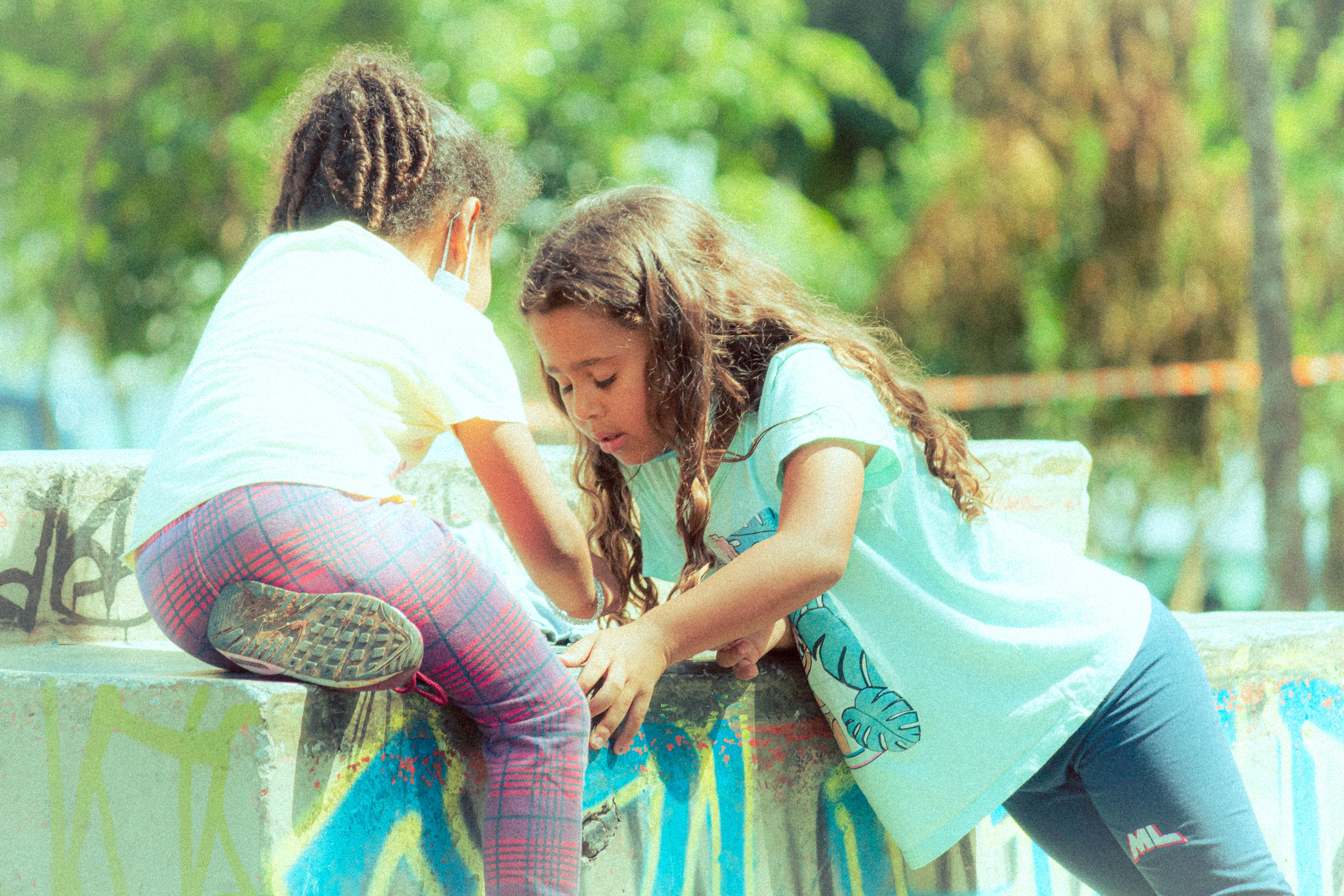 Fotomural Dos niñas jóvenes jugando sobre un concreto cubierto de graffiti en un parque al aire libre.