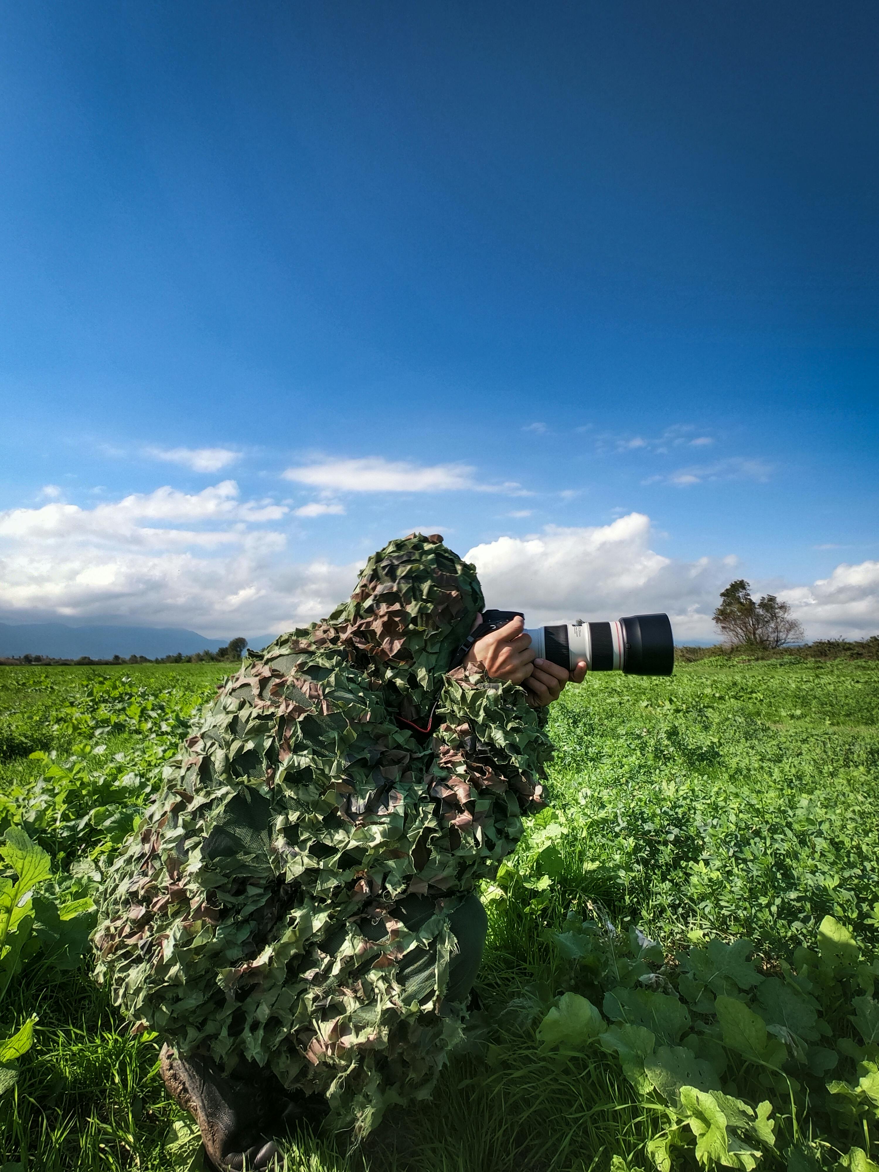 man wrapped in camouflage net