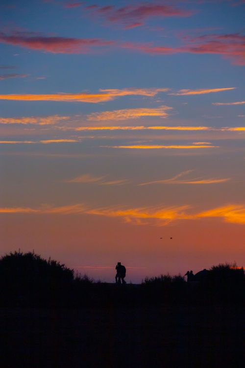 Free Silhouette of a couple embracing during a vibrant sunset. Stock Photo