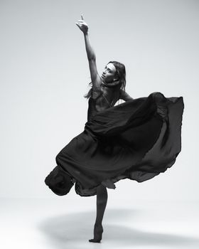 Black and white photo of a female dancer gracefully posing in a flowing dress.