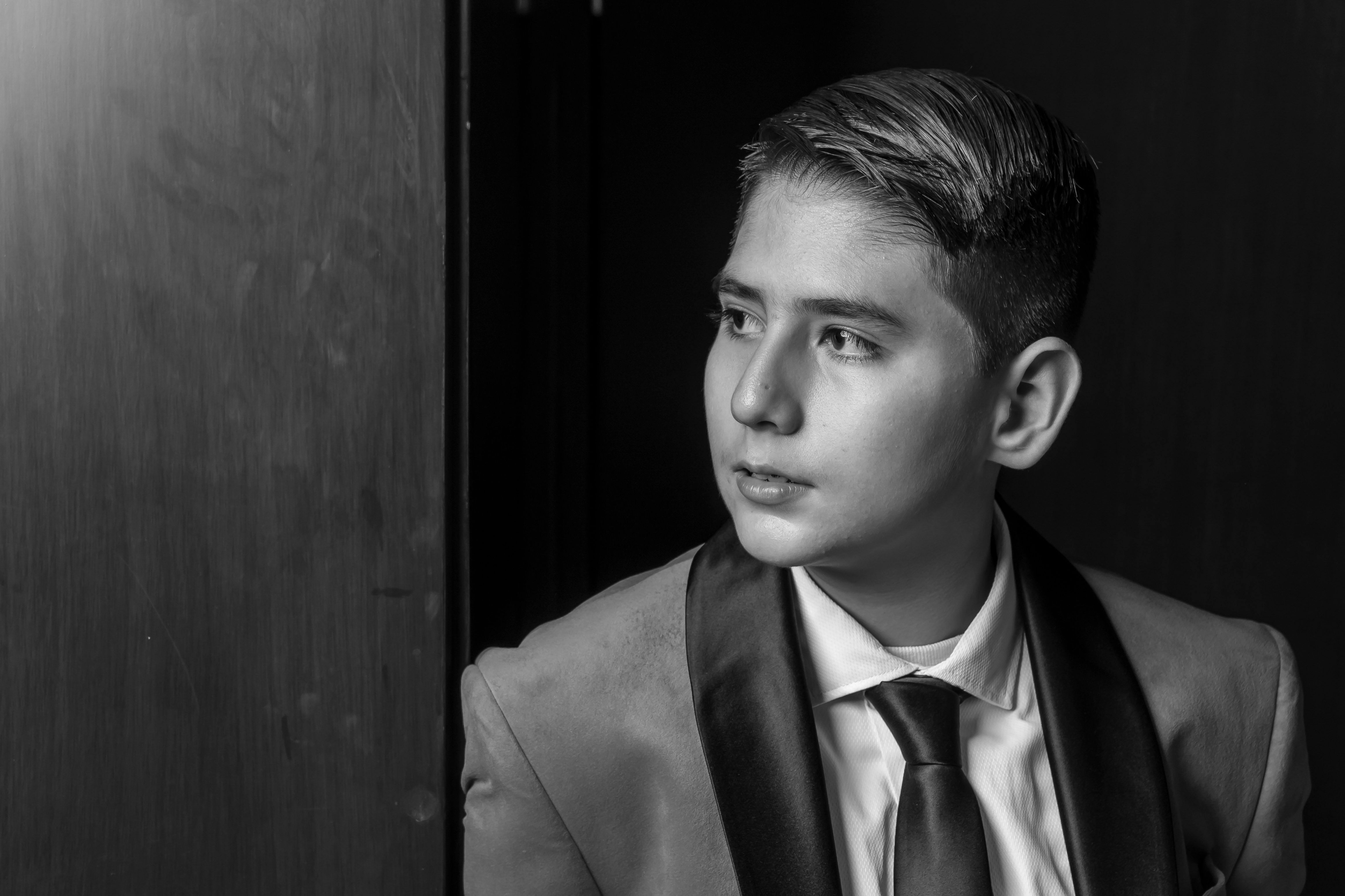 Elegant black and white portrait of a teenager in a formal suit, looking thoughtful.