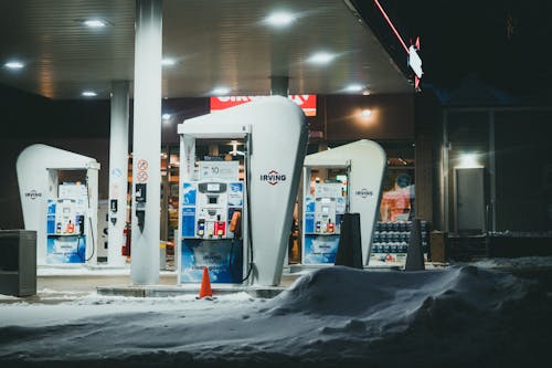 Illuminated Gas Station Covered in Snow at Night 