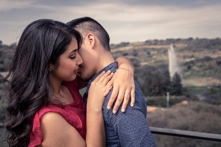 Fotomural Una pareja amorosa se abraza en una terraza al aire libre con vistas a un paisaje escénico.