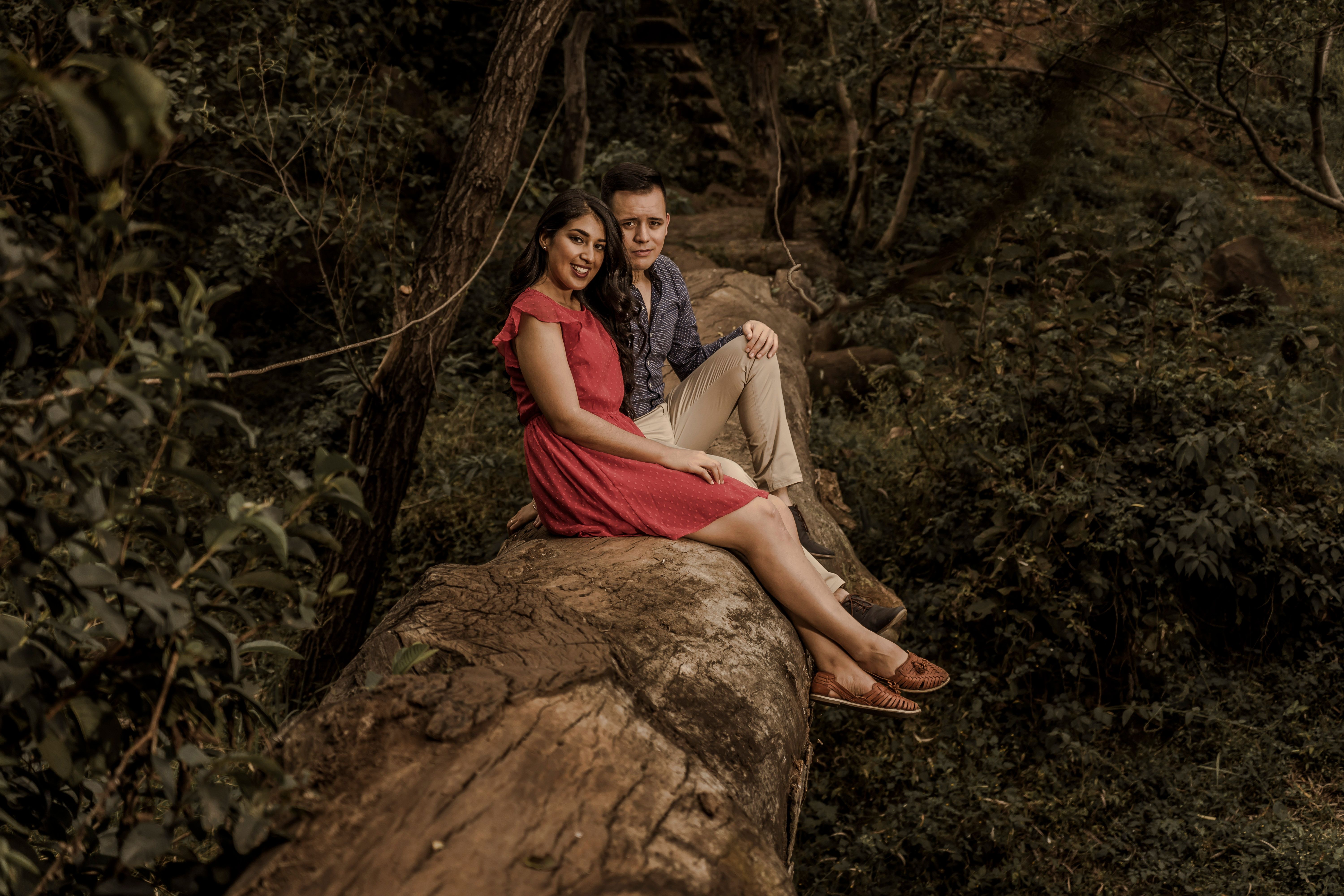 Fotomural Una pareja amorosa sentada en un tronco en un entorno forestal sereno, disfrutando de un momento pacífico.