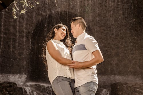Happy Couple Standing Against Waterfall
