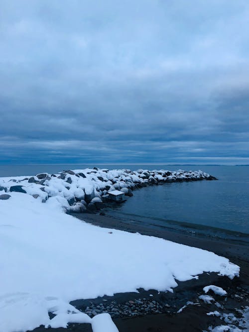 View of a Snowy Shore under a Cloudy Sky 