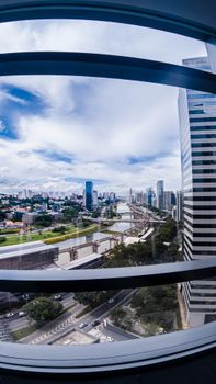 Dynamic fisheye view of a modern cityscape with skyscrapers and a river under a vibrant blue sky.