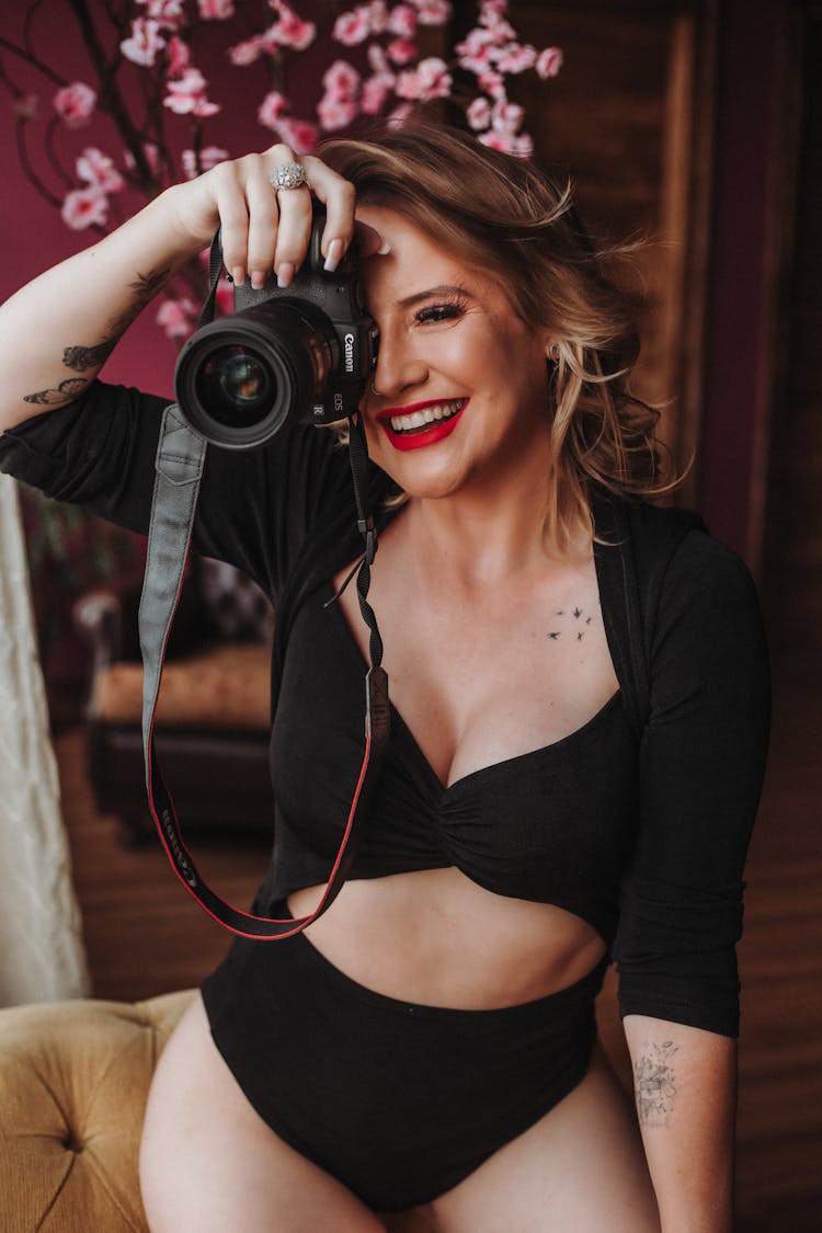 Blonde Woman Holding A Camera And Smiling 