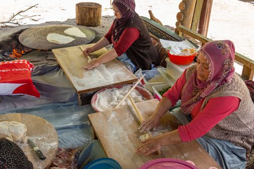 Free Women in headscarves making traditional Turkish flatbread outdoors on wooden boards. Stock Photo