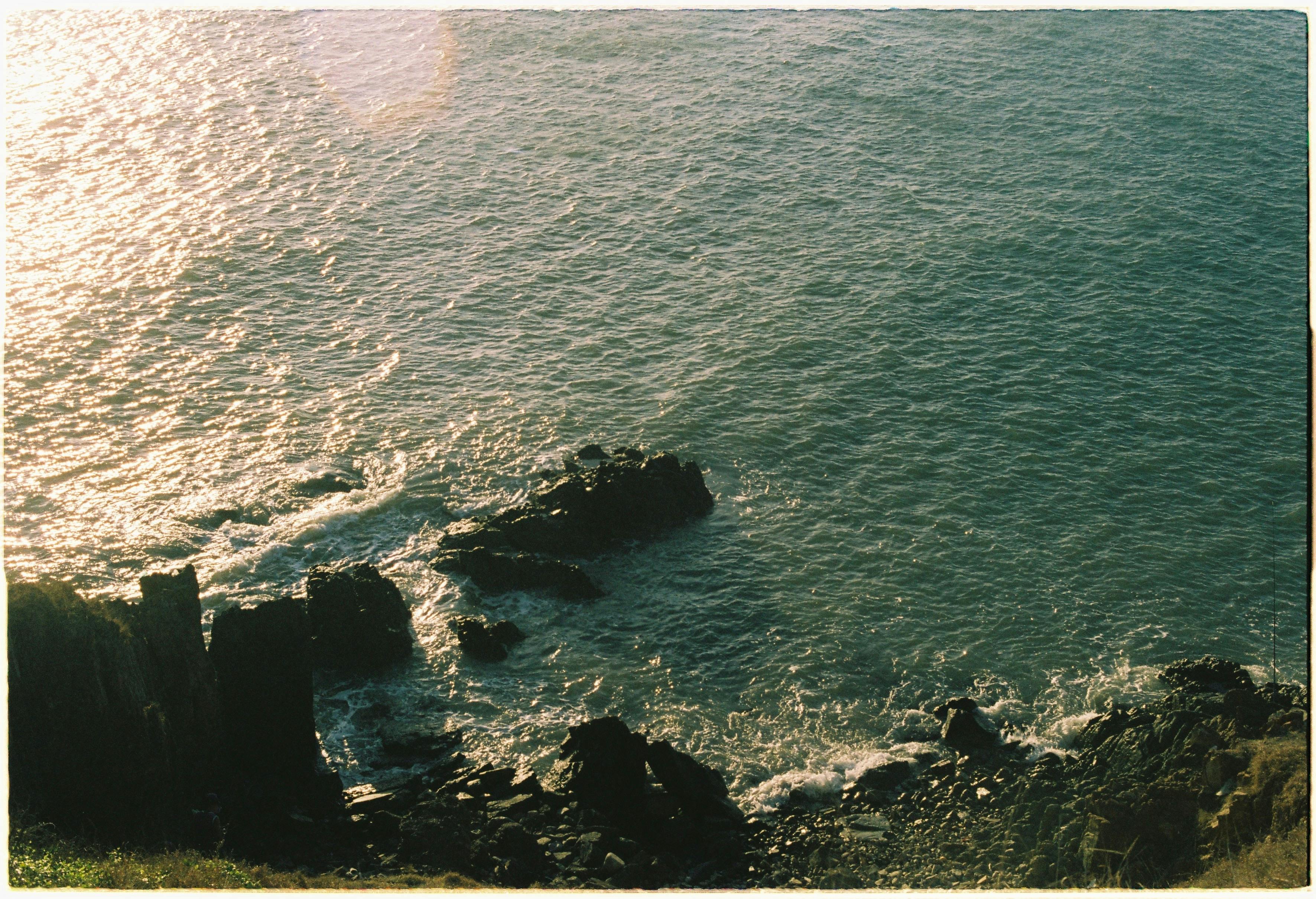 A peaceful view of a rocky seashore bathed in the warm colors of sunset, capturing the serene coastal ambiance.