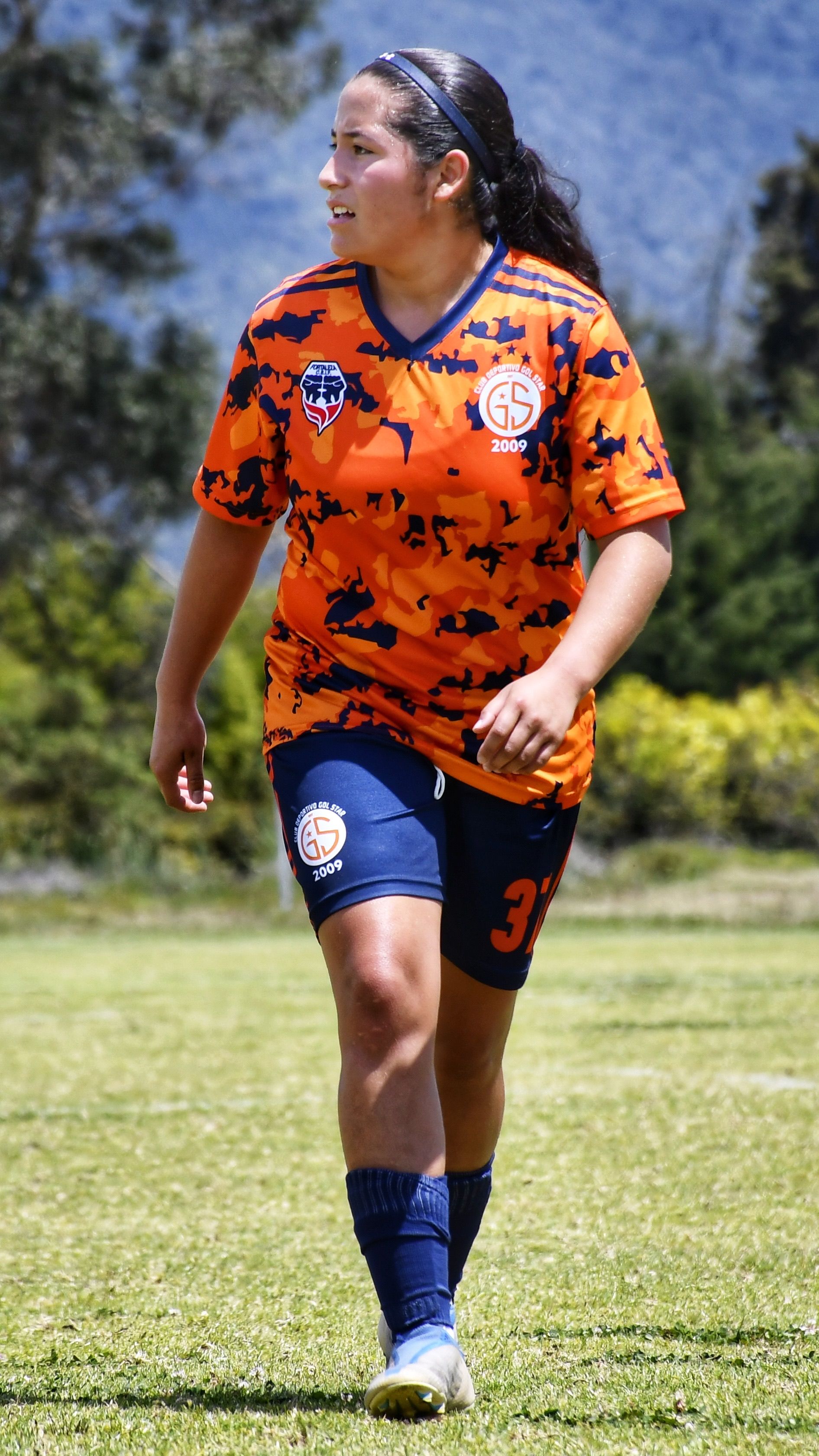 Teenage soccer player on outdoor field in vibrant sportswear.