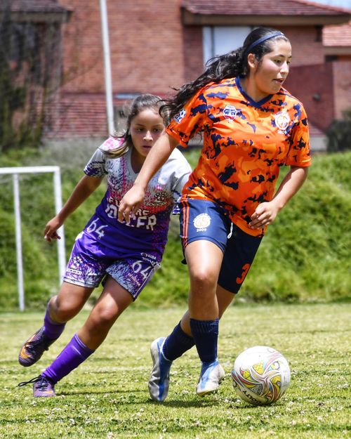 Free Two girls in vibrant soccer uniforms playing a thrilling match on a grassy field. Stock Photo