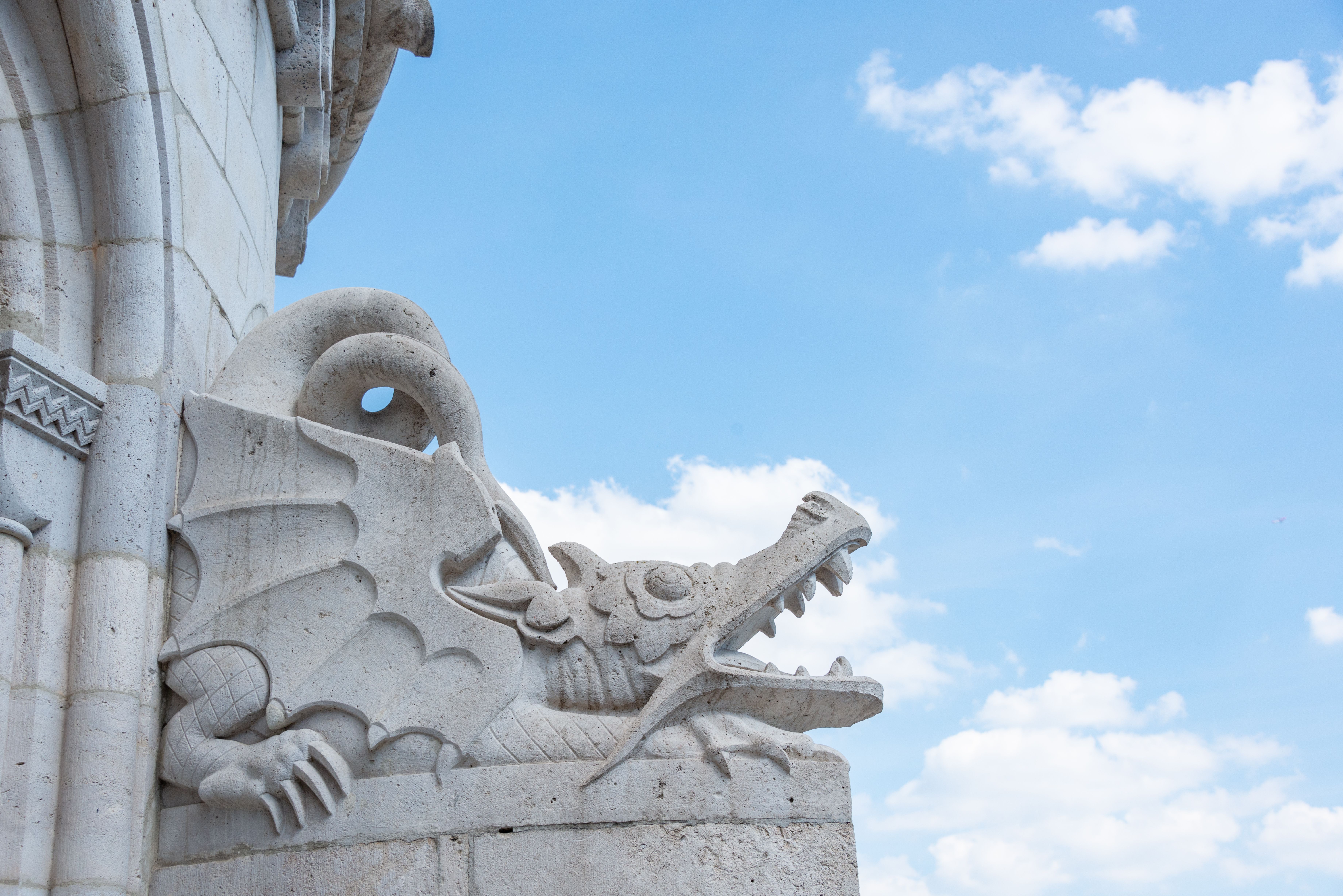Close-up of an intricate stone dragon sculpture set against a clear blue sky.