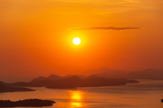A breathtaking sunset casting golden hues over tranquil islands and calm seas.