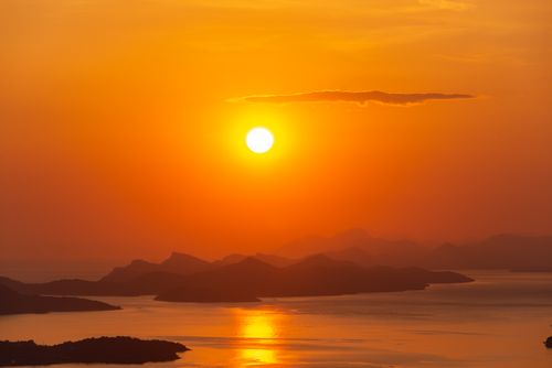 Free A breathtaking sunset casting golden hues over tranquil islands and calm seas. Stock Photo