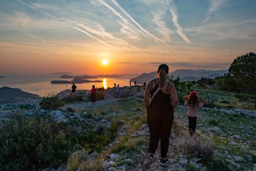 A group of people hiking on a coastal trail at sunset, enjoying breathtaking sea views.
