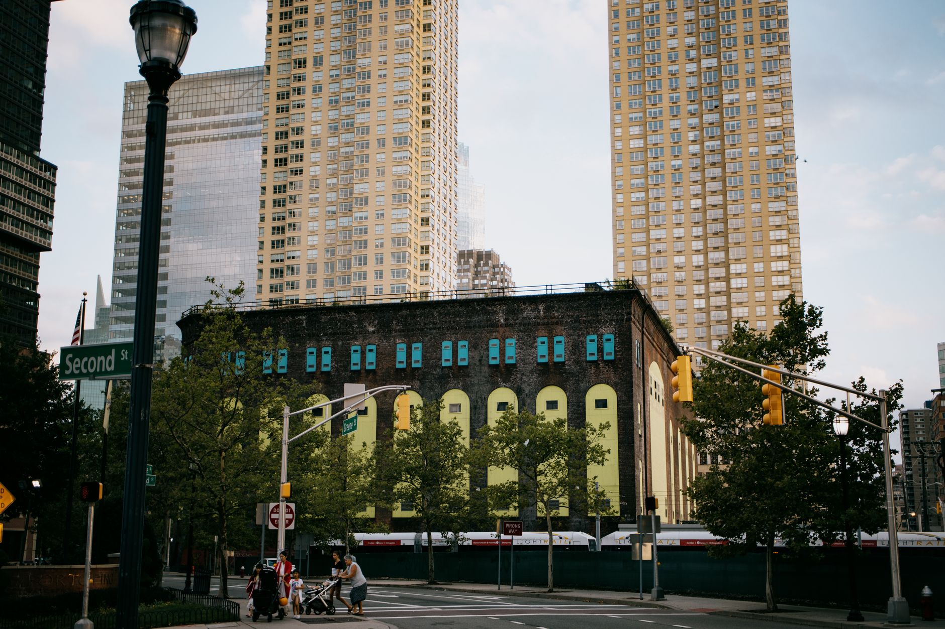 A vibrant intersection in Jersey City with towering skyscrapers and a historic building.