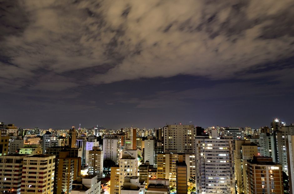 A dynamic city skyline at night showcasing towering skyscrapers under a cloudy sky.