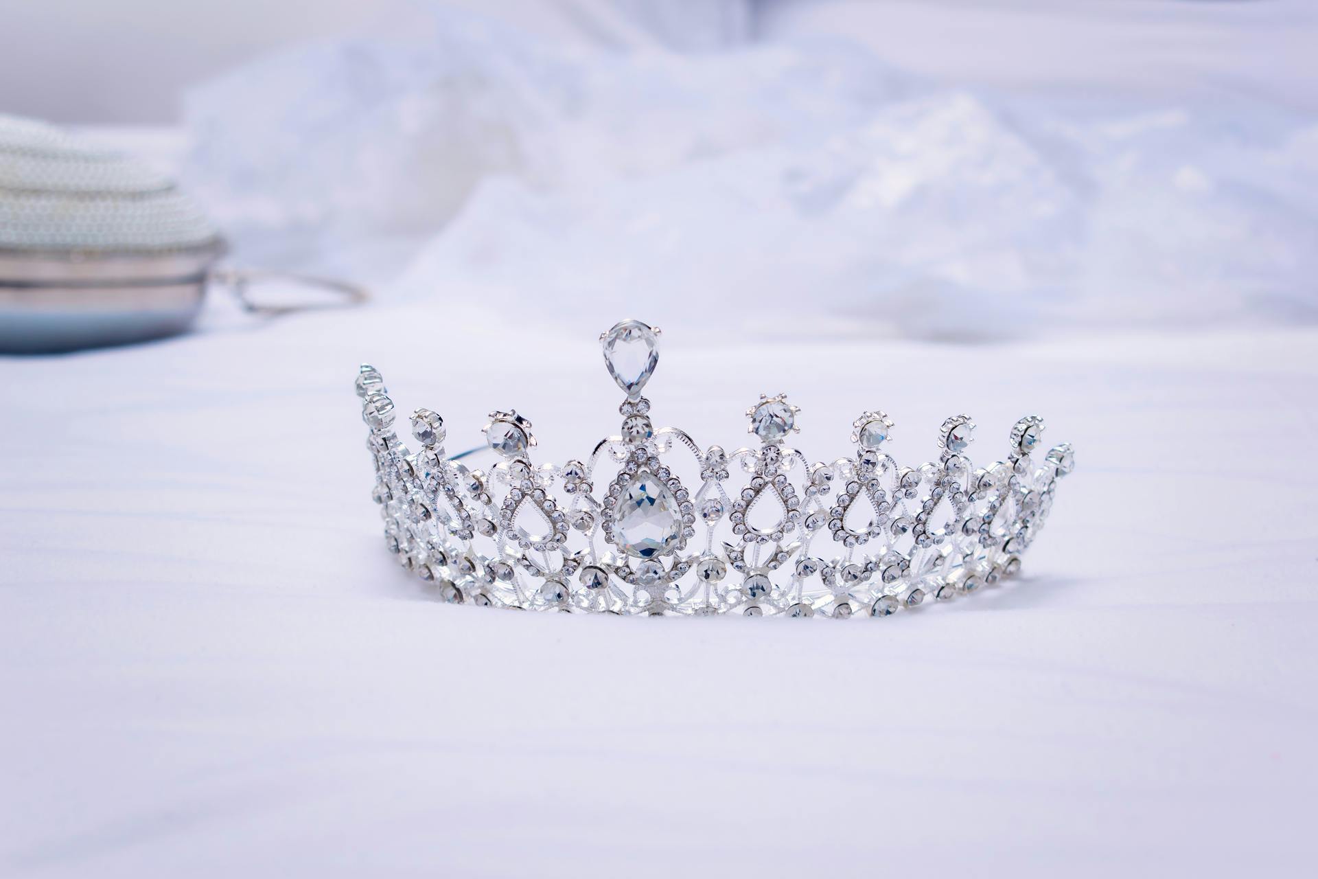 A luxurious diamond-studded crown symbolizing royalty and wealth rests on a serene white backdrop.