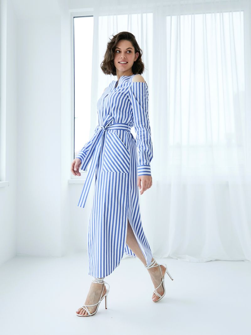 Woman in a blue striped dress walking in a bright room