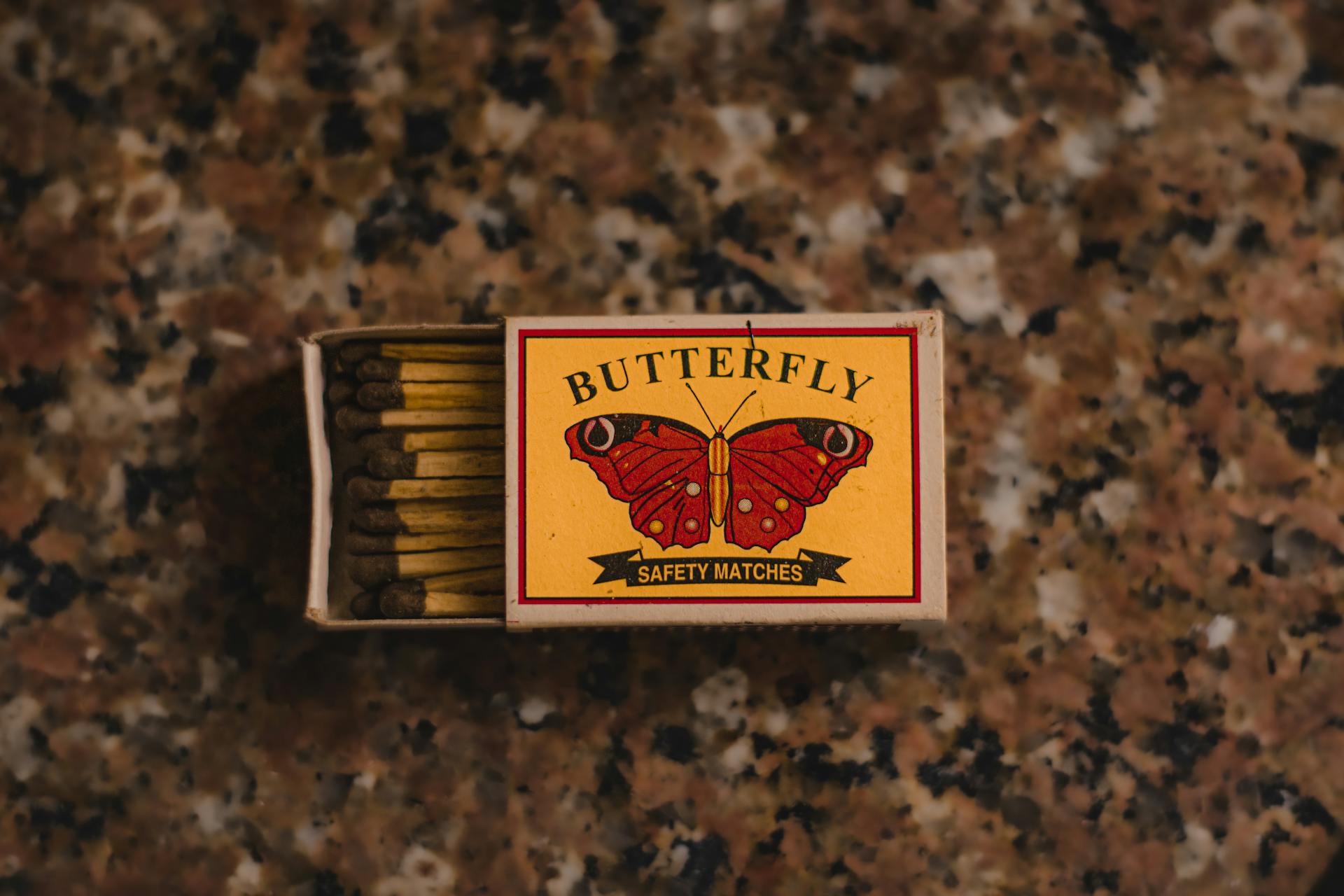 Vintage matchbox with "Butterfly Safety Matches" on a textured surface, perfect for creative design or retro themes.