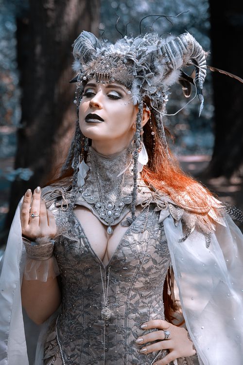 Free Enigmatic portrait of a woman in intricate fantasy costume and headpiece, standing outdoors. Stock Photo