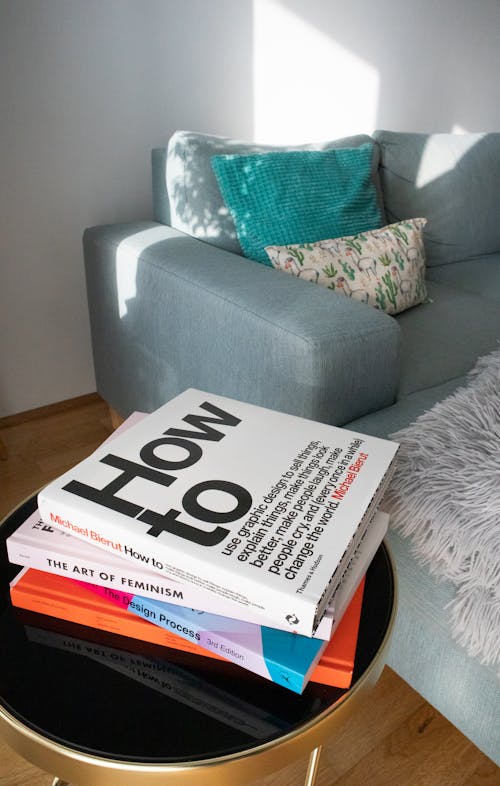 A Pile of Books Lying in a Table near a Sofa in a Living Room 