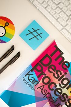 Top view of a creative workspace with design book, pens, and hashtag notepad.