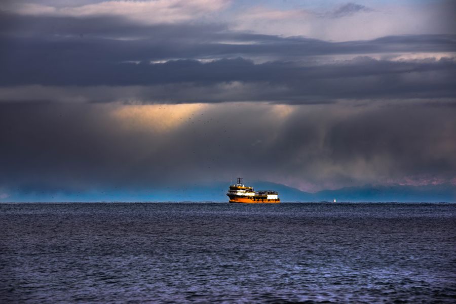 A solitary ship under dramatic storm clouds at sea — photo by Pavel Khlystunov on Pexels