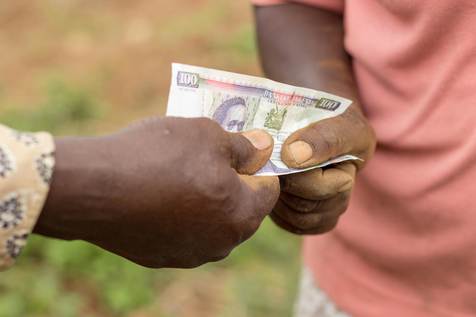 Captured moment of two individuals exchanging currency outdoors in Kenya.