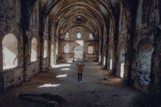 Man explores an abandoned historic church, spotlighting decay and adventure.