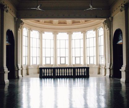 Bright hallway with white columns and high ceilings, featuring classic architectural elements.