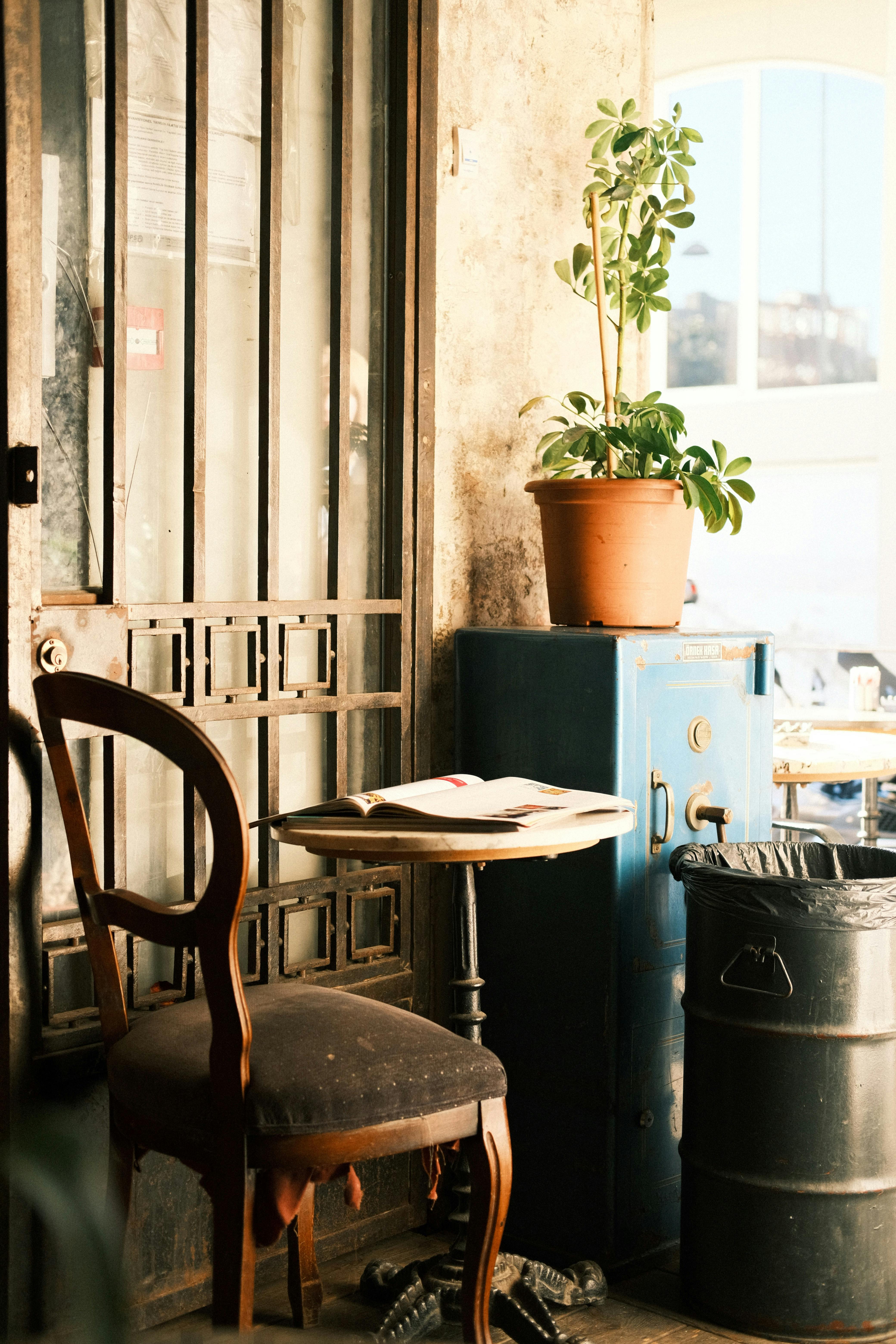 Free A warmly lit rustic corner with an armchair, table, and potted plant, capturing vintage charm. Stock Photo