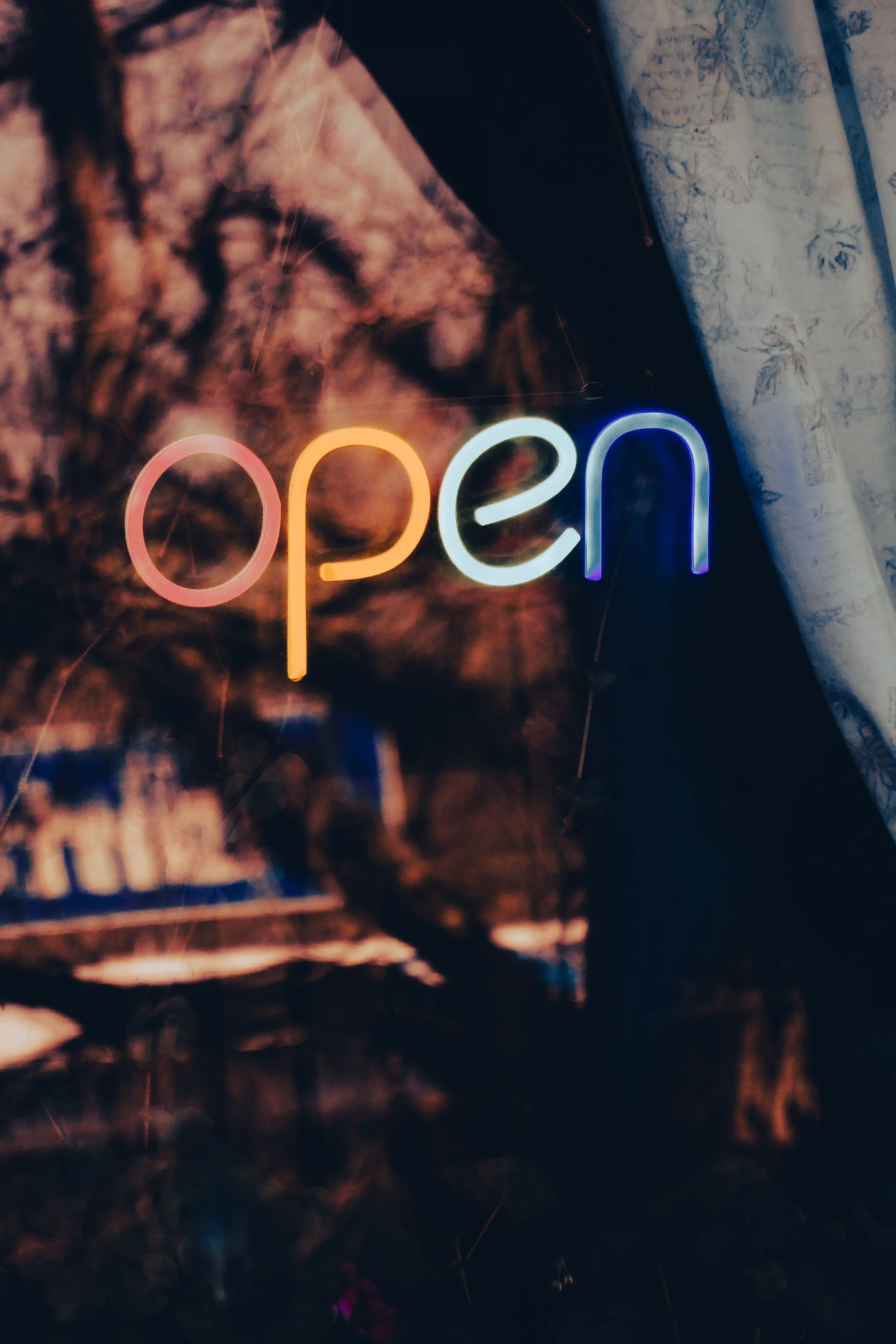 Colorful neon open sign glowing against a window, creating a vibrant urban atmosphere.