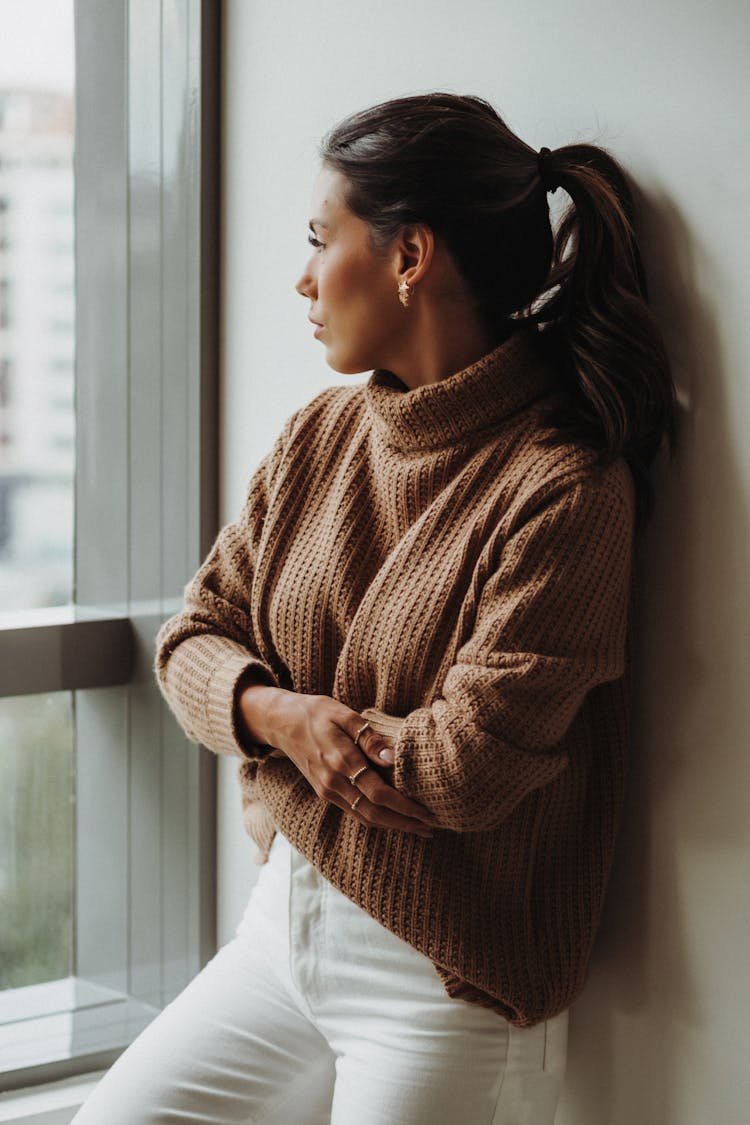 Woman In Brown Turtleneck And White Pants Standing Arms Folded 