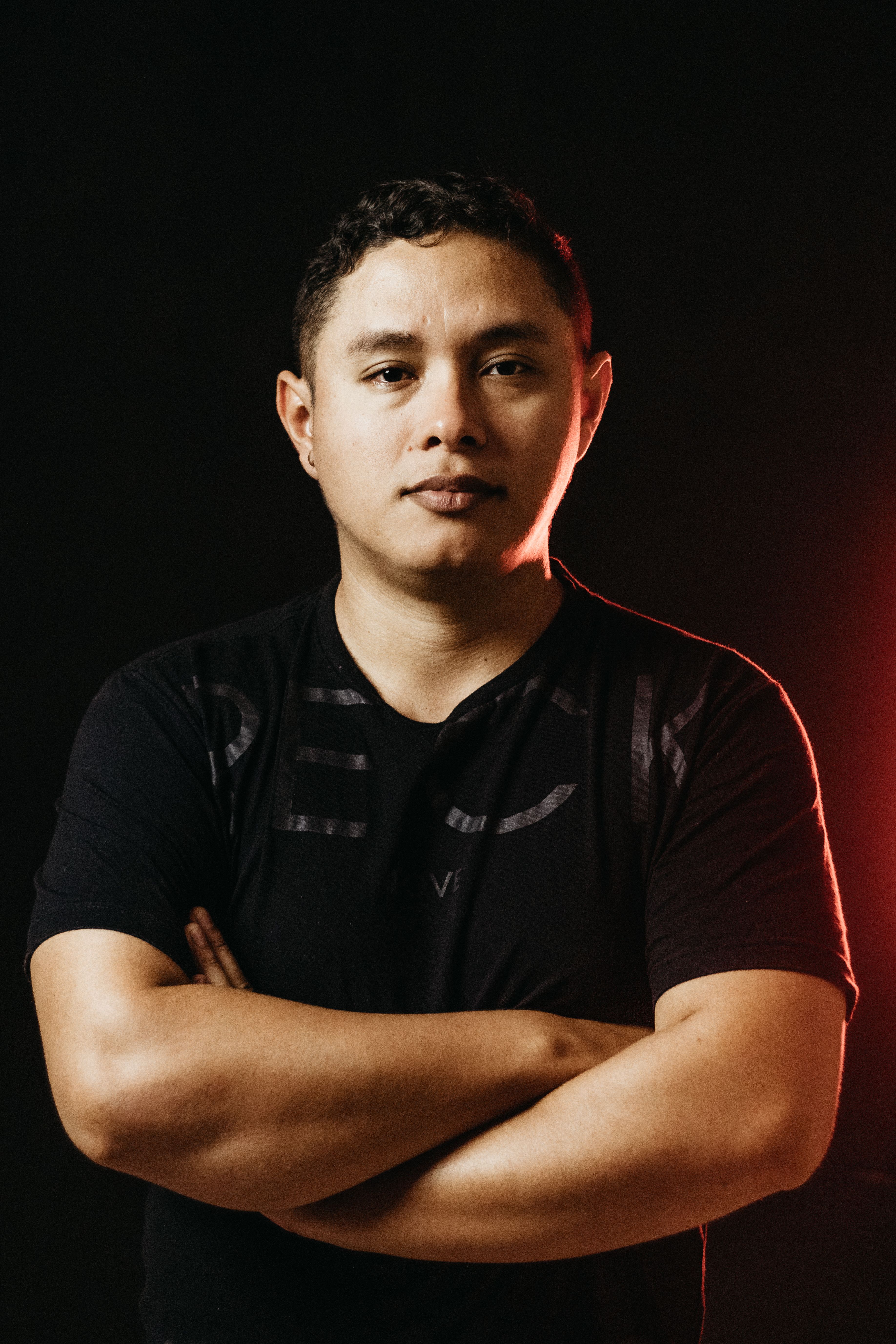 Confident man in a studio portrait with arms crossed and serious expression.