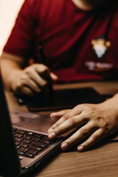 Close-up view of hands working with a laptop and tablet, illustrating modern technology use.
