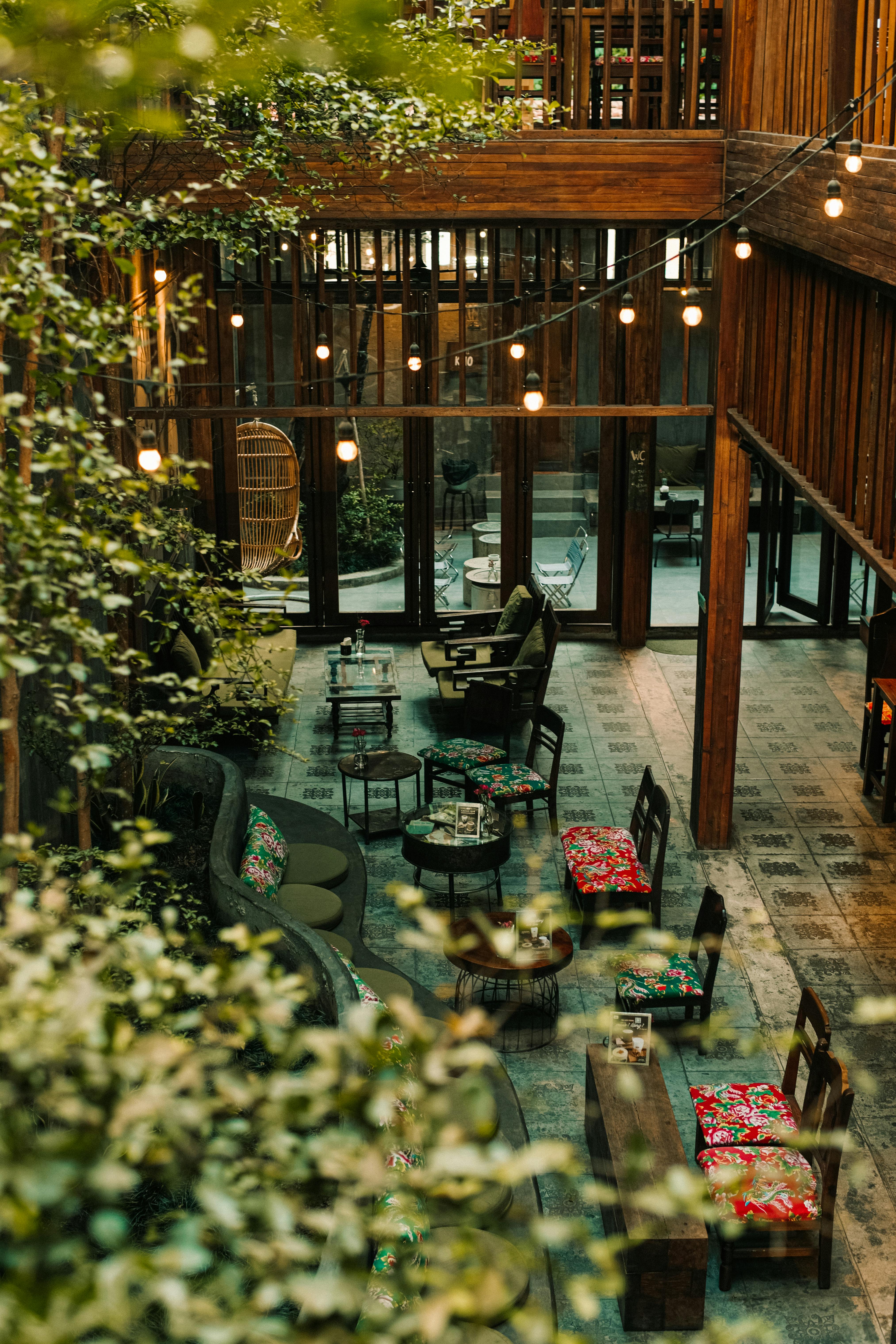 A charming indoor garden café with rustic wooden decor and ambient lighting.