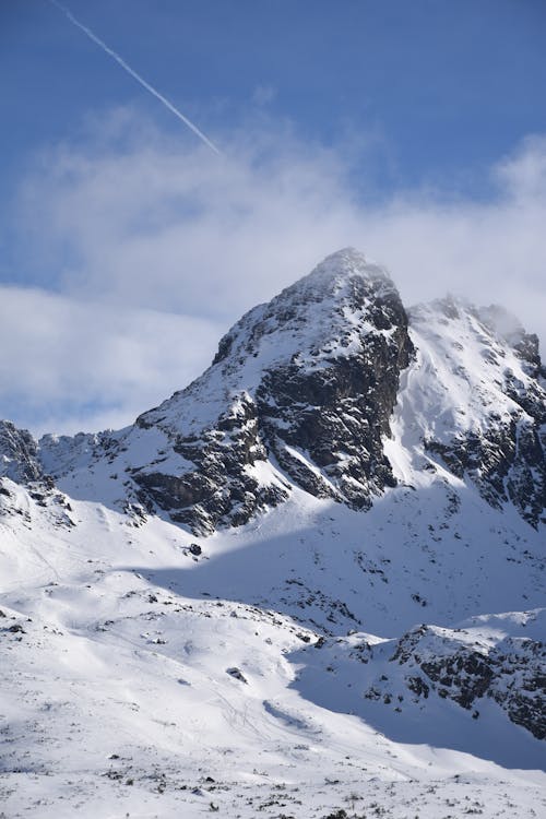 View of Rocky, Snowcapped Mountain Peak under Blue Sky 
