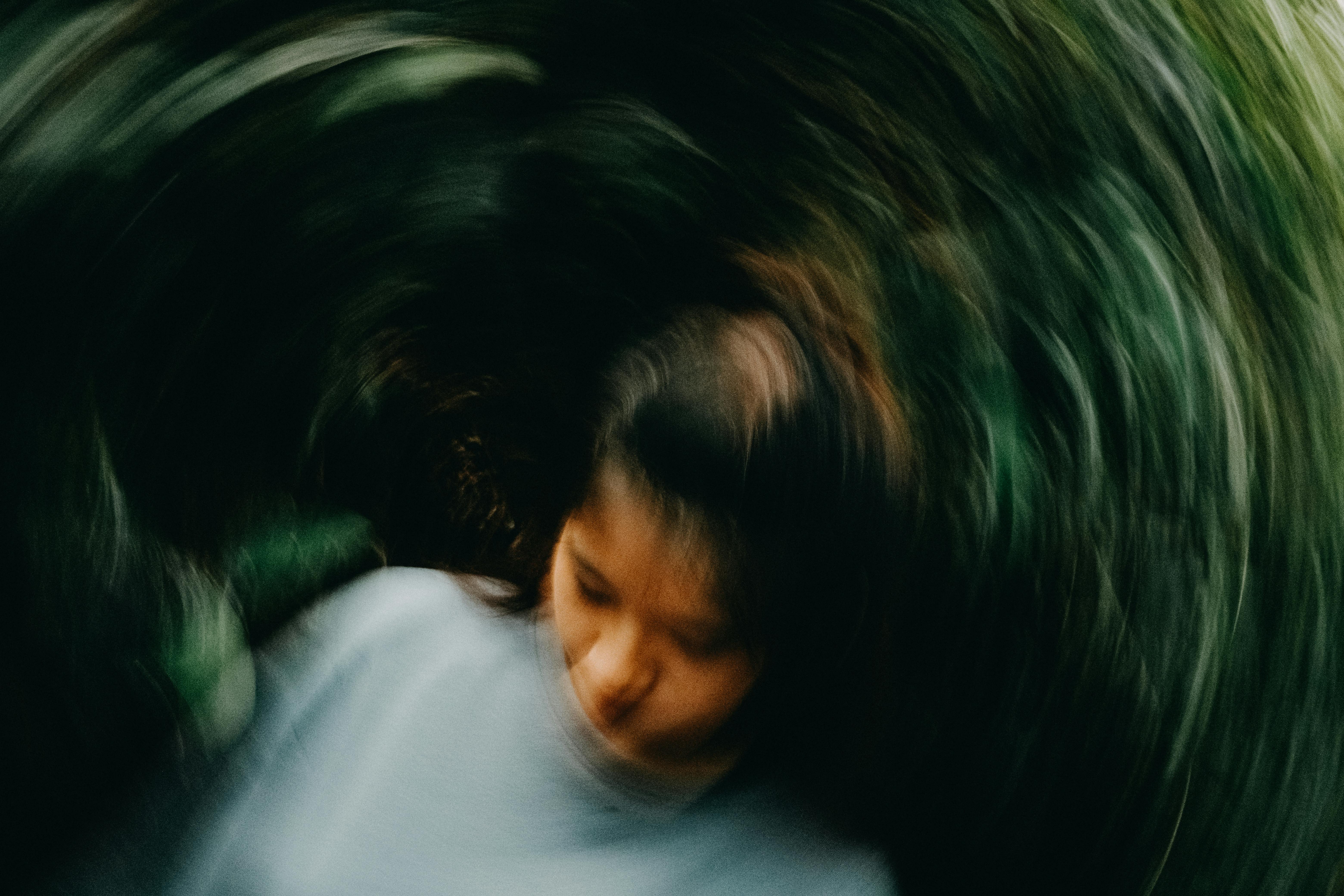Artistic blurred motion portrait of a young woman outdoors with abstract swirling effect.