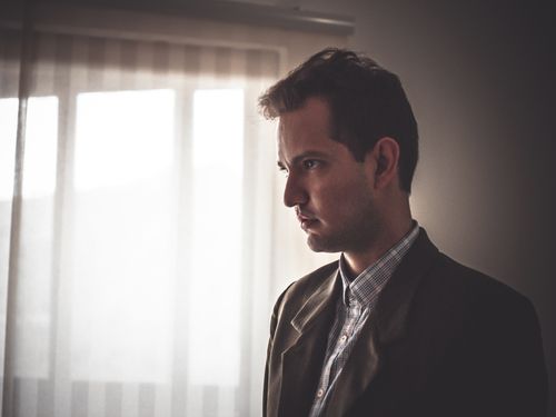 Free Portrait of a man in a suit posing elegantly indoors with soft natural lighting. Stock Photo