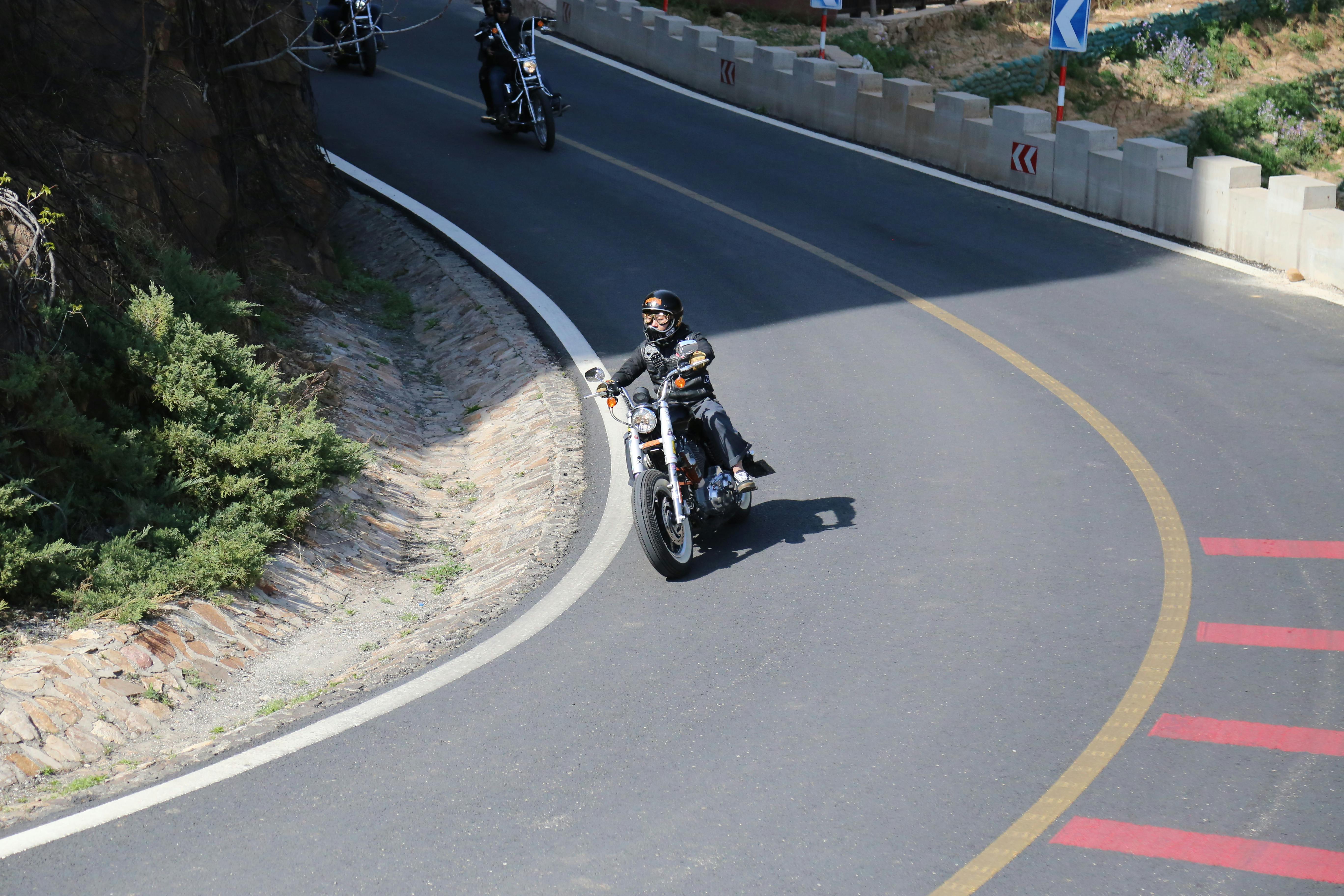 Motorcyclist on a winding road, enjoying a sunny day ride with a group, showcasing adventure and freedom.