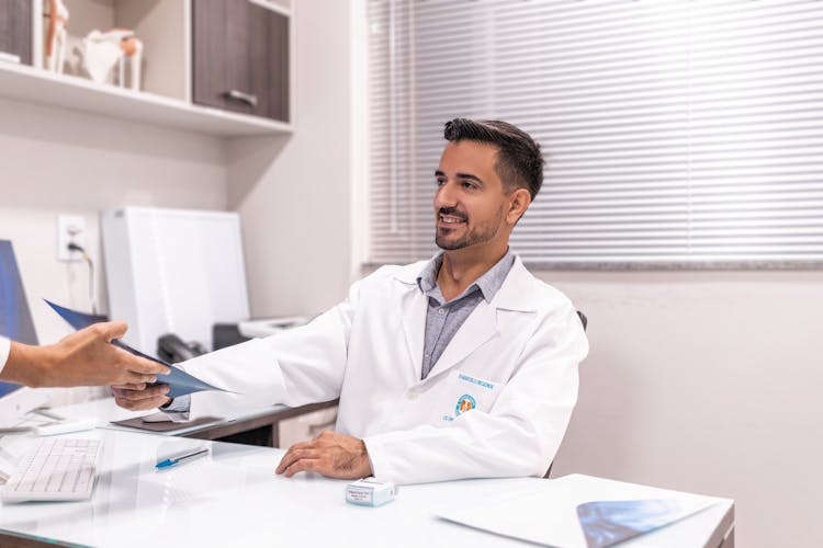 Person Handing Documents To Doctor