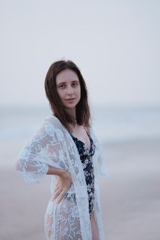 Portrait of a woman in a lace cover-up posing on the beach during the day.