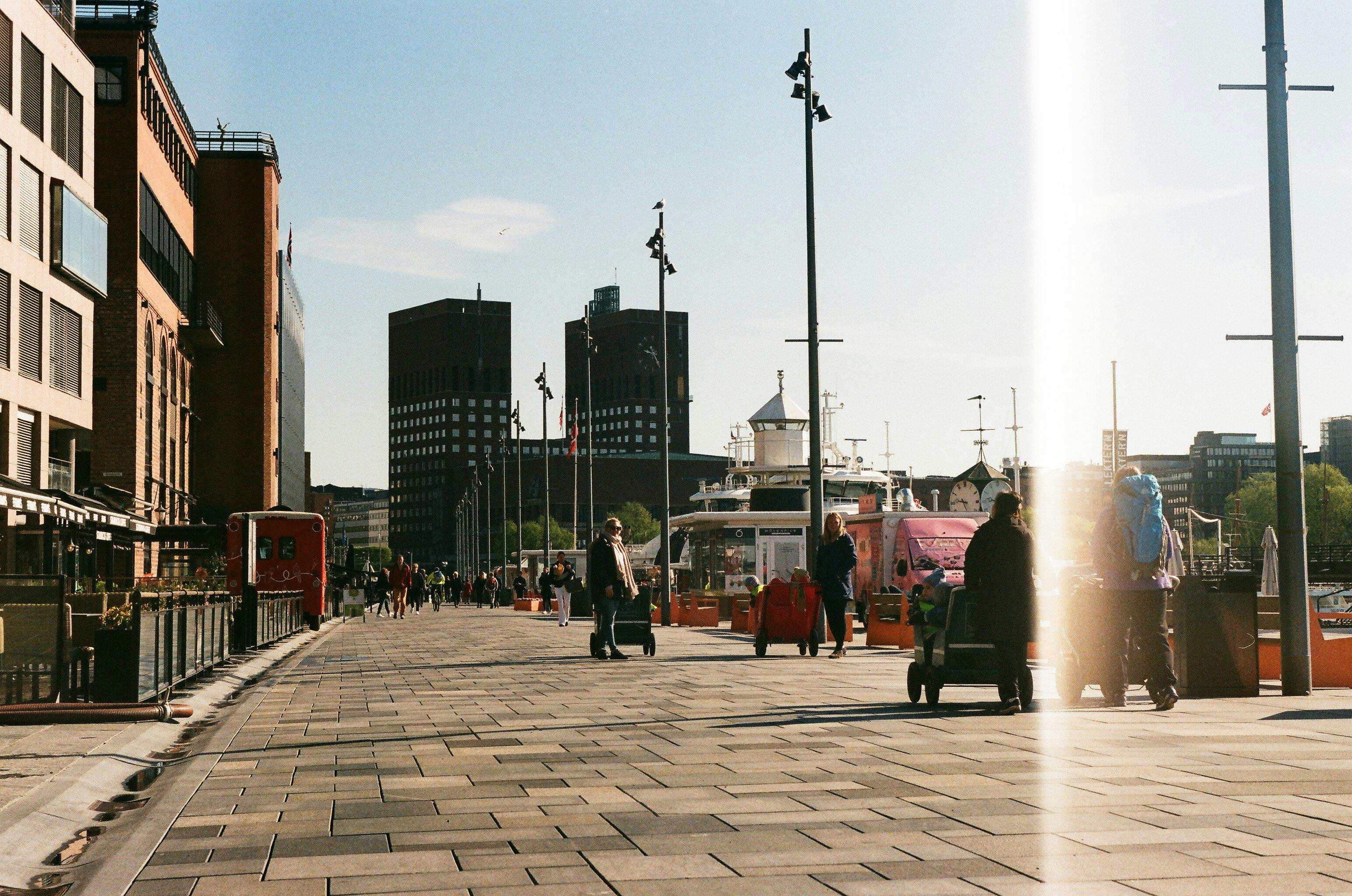 Folk spaserer ved Oslo rådhus en solrik dag
