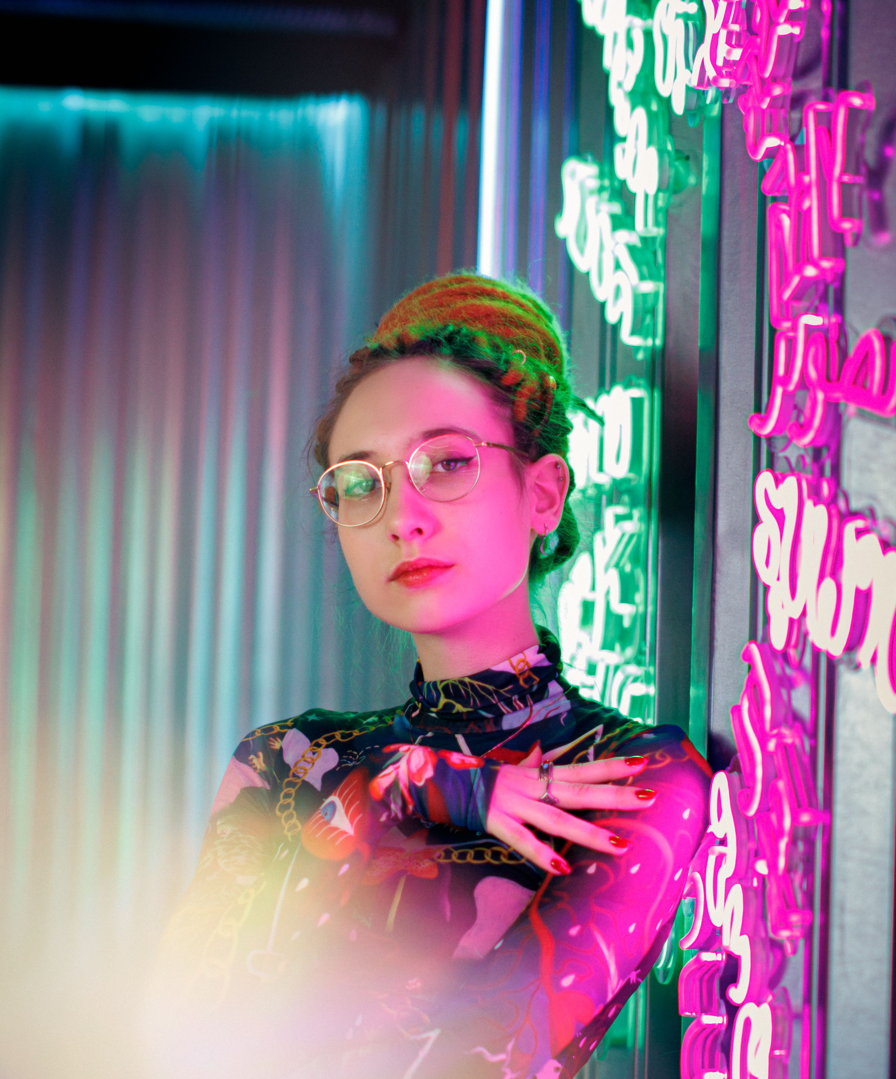 Stylish woman with glasses lit by coloured neon &mdash; photo by Daniil Kondrashin on Pexels