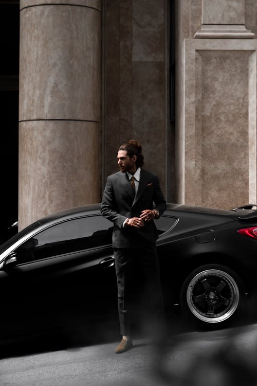 Well Dressed Man Standing next to a Luxury Black Car
