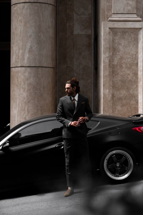 Free Well-dressed man in formal suit stands by a luxury car on an urban city street. Stock Photo