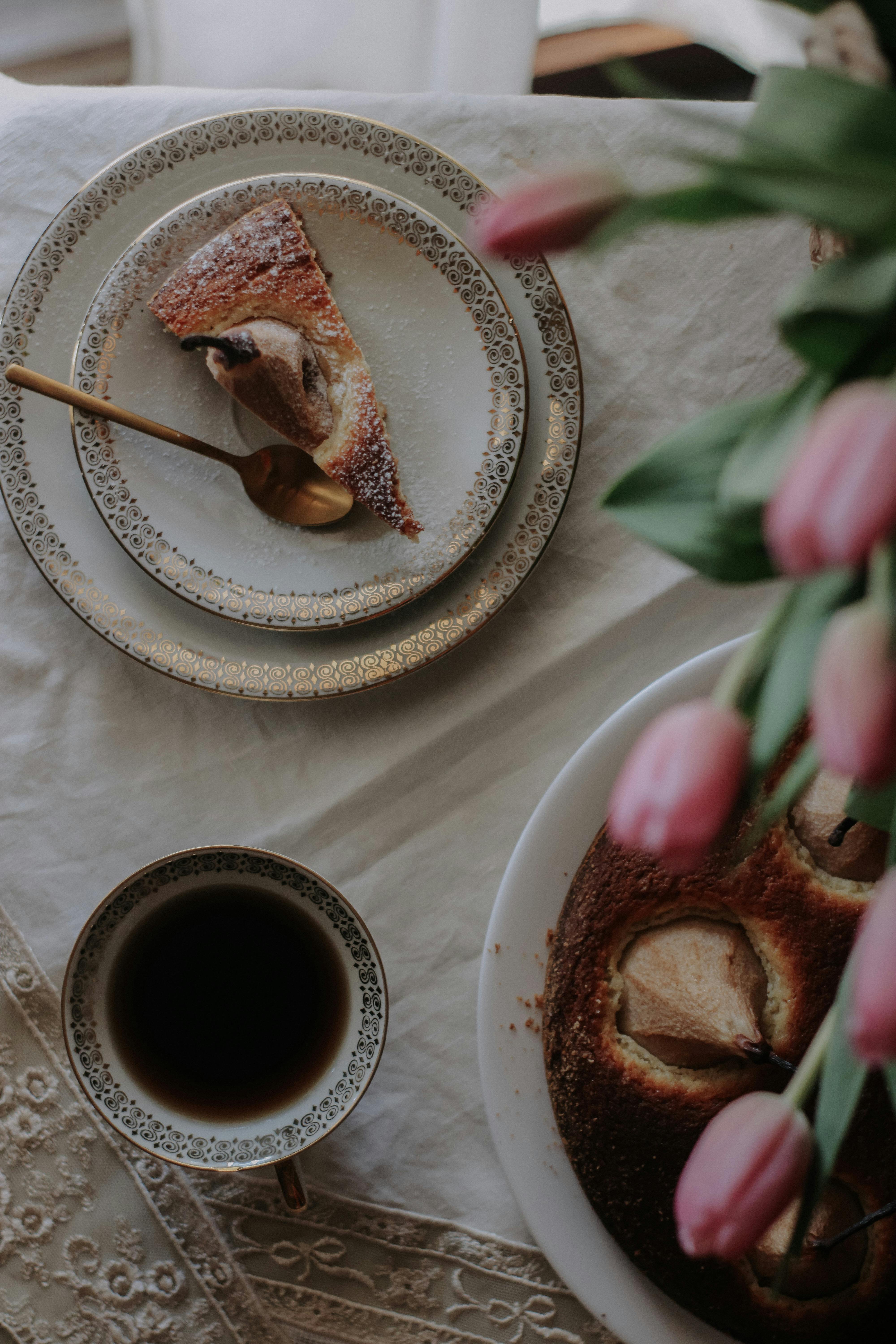 Top view of a breakfast table with cake, coffee, and tulips.